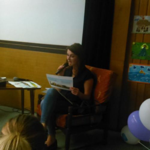 Zdjęcie przedstawiające Panią Eweline Rucińską czytającą książkę dzieciom w sali odczytowej Biblioteki Publicznej w Częstochowie
