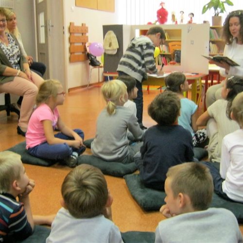Zdjęcie przedstawiące dzieci słuchające czytaną książkę