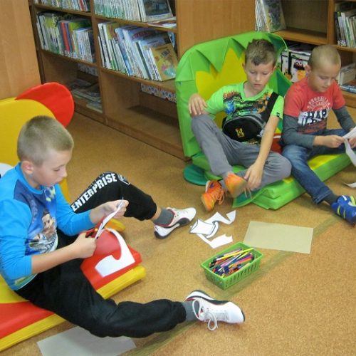 Zdjęcie przedstawiające dzieci siedzące na podłodze robiące prace konkursowe
