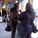 Infografika przedstawiająca reportera rozmawiającego z pasażerem w tramwaju